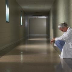 Doctor sitting alone in hallway with head down