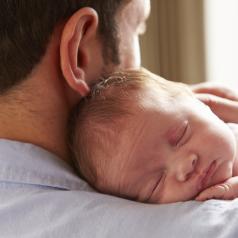 Father with newborn infant sleeping