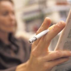 Close-up of cigarette while reading the newspaper