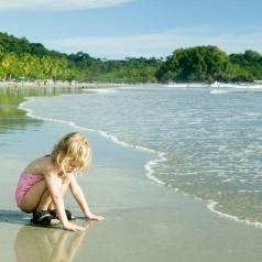 A small child crouches in waves at the seashore