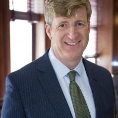 Patrick Kennedy standing in front of a window wearing a suit