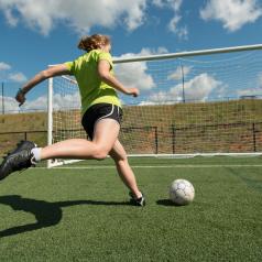 Woman about to kick soccer ball into net