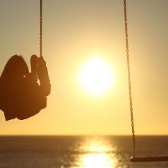 Rear view of a person on swing over the ocean