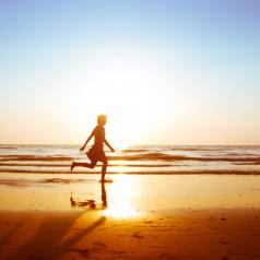 Silhouetted figure runs along beach