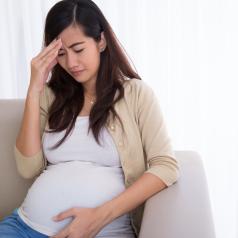 Pregnant woman sitting on couch with headache