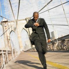 Blurred image of businessman running on bridge while checking watch