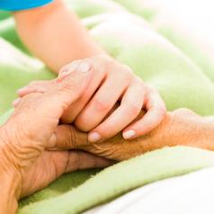 Young caregiver holding elderly person