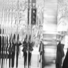 Black and white photo of blurred reflections of passersby 