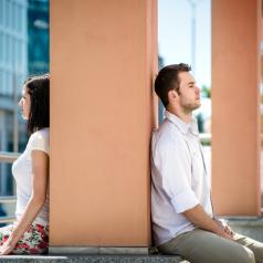 Couple sits on either side of pillar, backs to each other