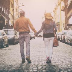 Rear view of couple walking down street holding hands