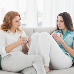 Female couple sits on sofa, deep in intimate discussion