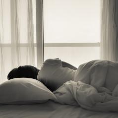 Woman laying in bed looking out window