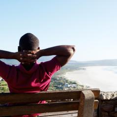 Athletic person sits on bench with hands behind head and looks out over city and lake