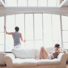 One partner sits on sofa, upset, while other partner, turns away to window