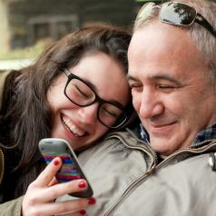 father and teen looking at phone