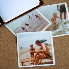 Open journal and three photos of a family at the beach lie on table
