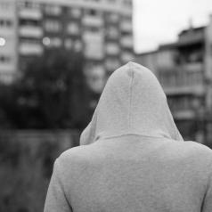 Grayscale photo of person in hoodie looking out toward city