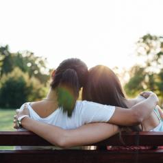 Closeup rear view photo of teen and parent with ponytail sitting on park bench