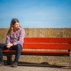wearing plaid shirt casual style relaxing outdoor at summer sunny windy day sitting on bench