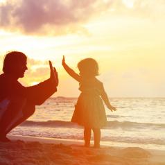 Child gives father a high-five at the beach