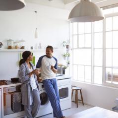 Shot of a young couple talking and drinking coffee in a spacious white kitchen