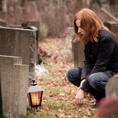 person crouching at grave stone
