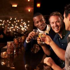 Diverse group of men at fancy bar with wood counters and soft lights