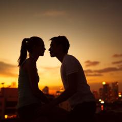 Couple silhouette against city skyline at sunset
