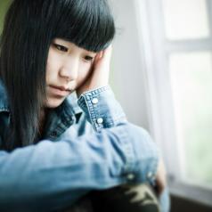 Sad teen girl sitting next to window