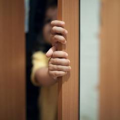 child hiding behind door