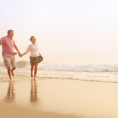 senior couple hand-in-hand outdoors on the beach