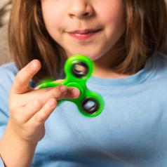 Kid plays with green fidget spinner toy