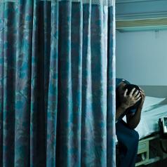 Doctor sitting on hospital bed behind curtain