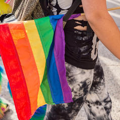 Side view of a person holding Pride flag at parade walking with others
