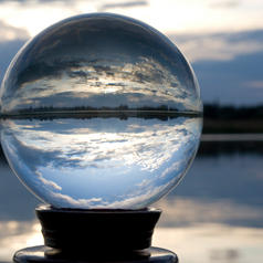 Crystal ball on stand by sea reflects cloud and sea view