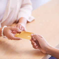 Cropped shot of person with pearl bracelet handing credit card to cashier