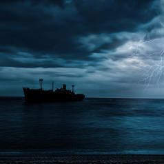 Cargo ship sails across darkening sea with lightning against the sky