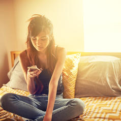Teenager using smartphone in bedroom