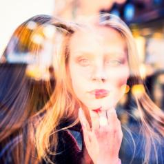 Double exposure image of woman on street in two places at once with long blonde hair, looking out