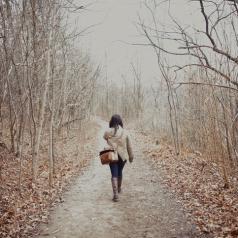 Rear view photo of young person in coat with bag and long hair out for a hike in late autumn