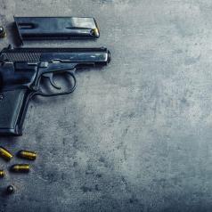 Handgun and bullets are spread across dark concrete table