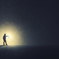 Person holding lamp out ahead walks through dark area