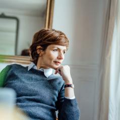 Thoughtful professional wearing sweater with short hair sits in comfortable office looking out window