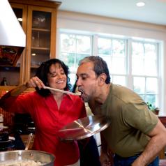 A couple who has reached middle age cook together in the kitchen, smiling and enjoying themselves
