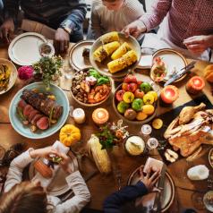 Overhead photo of people seated around table filled with Thanksgiving dishes
