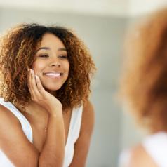 Person with natural hair looks into mirror smiling widely