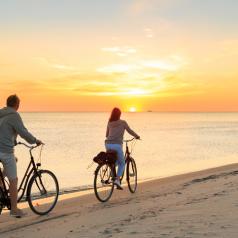 Couple enjoys twilight ride along beach on bikes