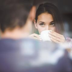 Woman sipping drink and looking at partner on date