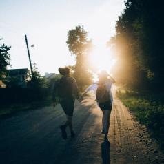 Couple holding hands and running into sunset on a country road