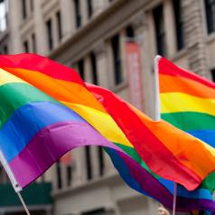 Two Pride flags fly on New York street during a Pride parade